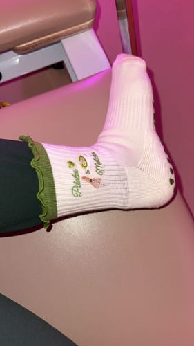 Reviewer's foot in the white Pilates & Matcha grip sock with a green ruffled cuff.