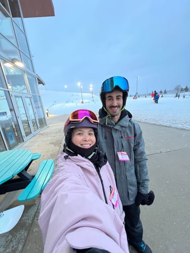 Reviewer smiling in her roomy pink snow jacket on a ski slope with a friend.