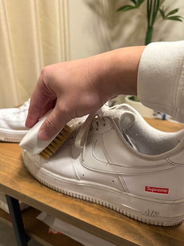 購入者がプレミアム洗浄ブラシで白いスニーカーをきれいにしている様子。