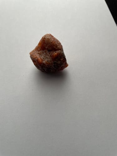 Photo d'un client : un morceau de pierre de soleil brute de couleur orangée sur une surface blanche.