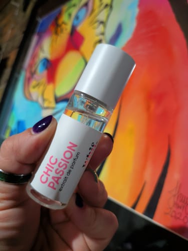 Customer's hand holding a small glass bottle of Chic Passion extrait de parfum.