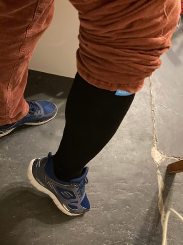 Reviewer wearing the black Performance Eucalyptus Compression Socks with a sneaker, showing the fit on their lower leg.