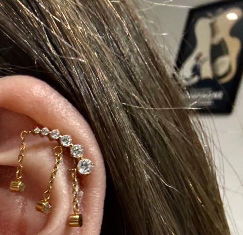 Close-up of a customer's ear showing the Drippy Chained Flatback Gold earring worn on the helix.