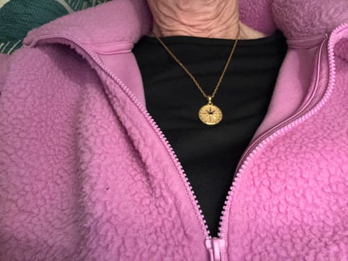 Customer wearing a gold compass pendant necklace from their December Bundle.