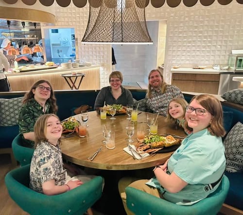 Reviewer wearing the Disney's The Muppets "Light the Lights" shirt while dining with family at a restaurant.