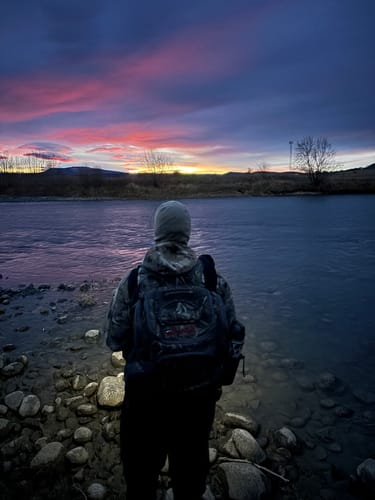Customer in hunting gear by a river at sunset, the setting for their GS Extreme 3.0 review.