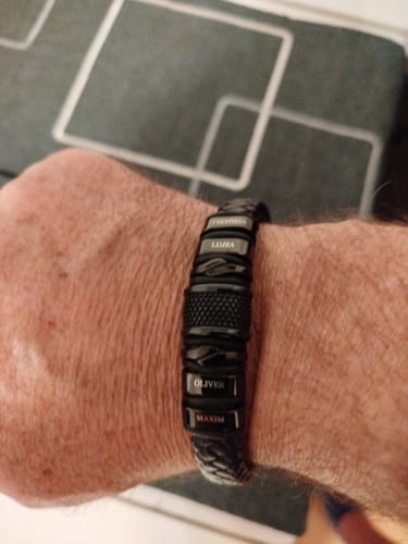 Customer wearing the personalized black bracelet on their wrist, showing the small engraved name pendants.