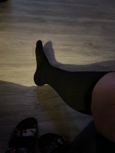 Recensent som visar en svart, ribbad Diasocks stödstrumpa på benet.