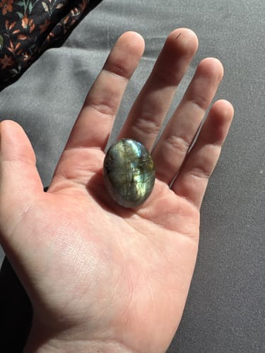 Customer's open hand holding a polished labradorite crystal, showing its unique color shift.