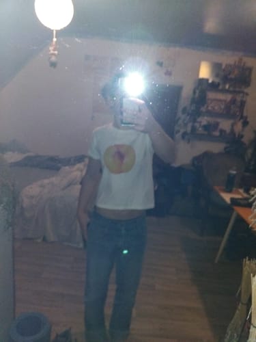 Reviewer wearing the 'you're a peach! baby tee' in a mirror selfie taken in their room.