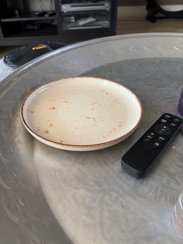 Recensent toont een glanzend beige bord van de Loods serviesset op een tafel.