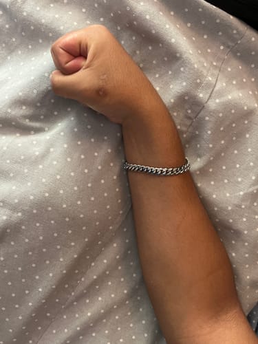 Cliente mostrando su Pulsera Cuban de 8mm en la muñeca sobre una superficie de lunares.
