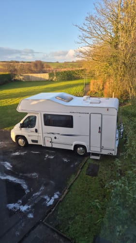 Customer's white motorhome with a clean roof after being washed with Citrus Wash, with suds on the driveway.