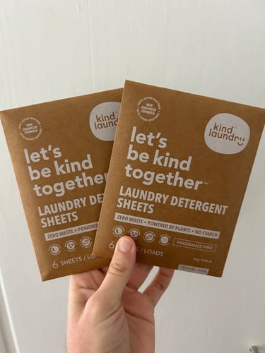 Customer holding two small packets of the Travel Size Fragrance Free laundry detergent sheets.