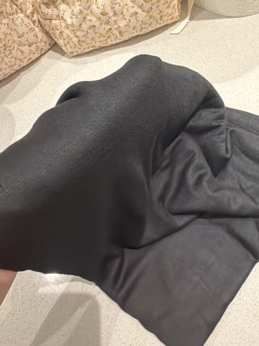 Customer holding the Premium Jersey Hijab, showing a close-up of the soft, dark fabric.