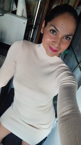 Customer poses in the Ribbed-Knit Asymmetric Top and matching skirt, showing the form-fitting style and mock neck.