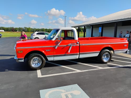 Reviewer's image of a vintage red and white pickup truck parked in a parking lot.