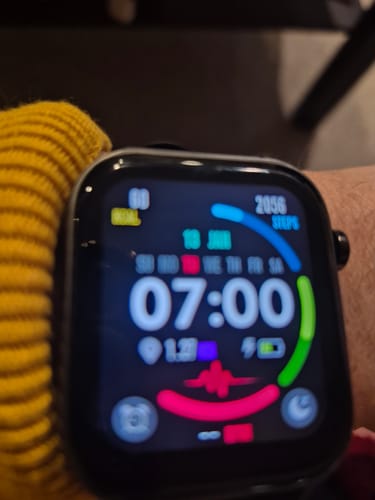 Close-up of a reviewer's smartwatch on their wrist, showing a colorful display with steps and heart rate data.