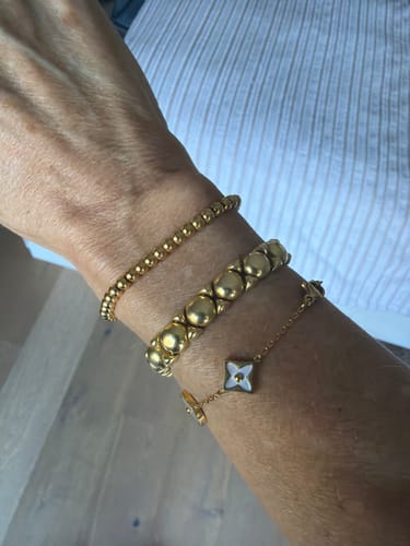 Reviewer's Niloya Beaded Gold Bracelet stacked with two other gold bracelets on their wrist.