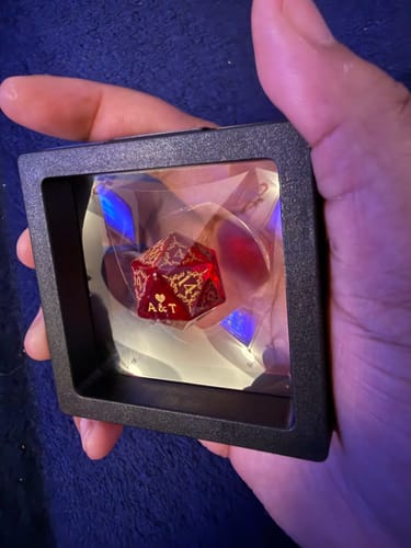 Customer holding a display case showing the red and gold personalized Dice Necklace pendant.