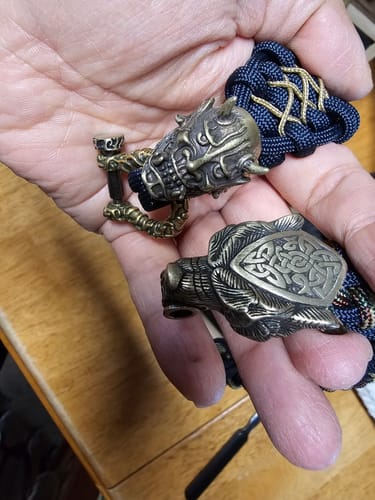 Customer's hand holding the detailed Oni Paracord Bracelet alongside another bear-themed bracelet for comparison.