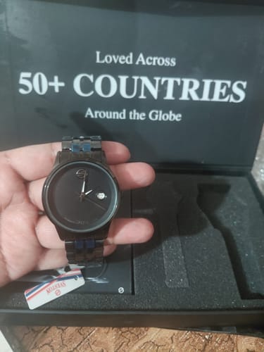 Customer's hand holding the black Onyx watch over its open packaging.