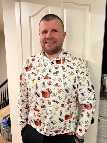 Customer wearing the white 'Bon Rat-Pétit' Performance Hoodie, showing the fit and colorful all-over Ratatouille print.
