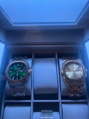 Customer's two Lucky Fours® Brone watches, one with a green dial and one gold, displayed in a watch box.