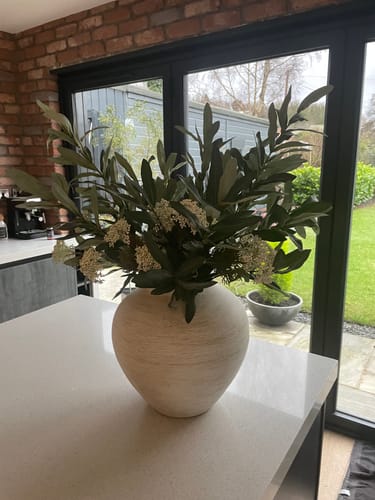 Customer's Faux Olive & White Berry arrangement displayed in a large, textured white vase on a kitchen island.