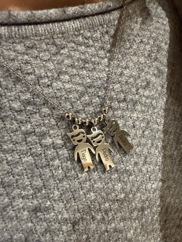 Customer wearing the silver-colored Family Bond necklace with three personalized child-figure pendants.
