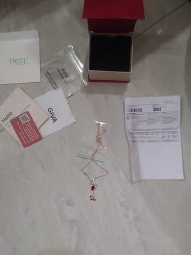 Customer's Rose Gold Glory of Love Necklace with its branded box, certificate, and shipping invoice on a floor.