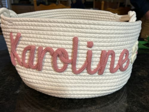 Customer's white, personalized knitted basket with the name "Karoline" in pink yarn.