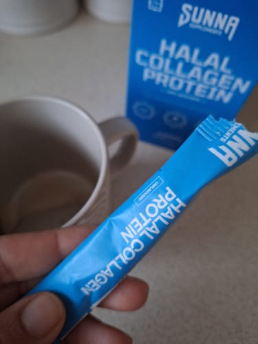 Customer holds a single blue Halal Collagen Protein sachet, with the product box and a mug in the background.