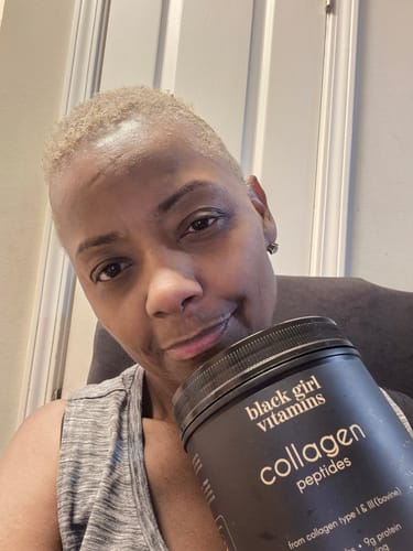 Reviewer smiling while holding a black container of BGV Collagen Powder.