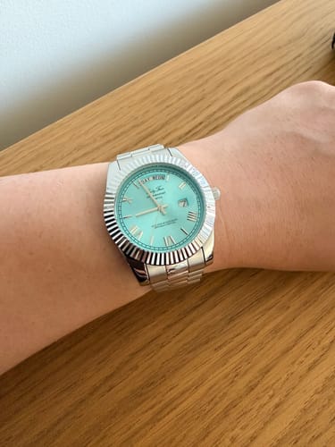 Customer's wrist wearing a silver-colored watch with a fluted bezel and bright blue dial.