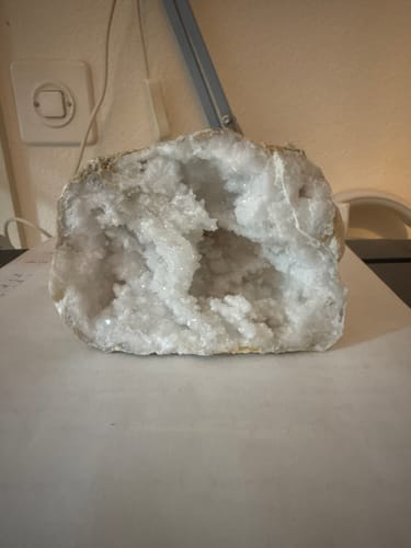 Photo d'un client : une géode de quartz blanche et cristalline posée sur une table.