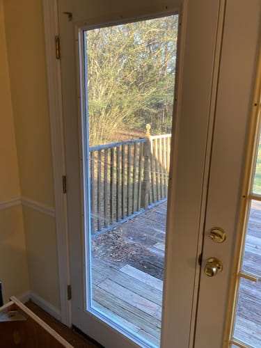Customer's new white Full Lite Frame Kit installed on a glass panel door leading out to a wooden deck.