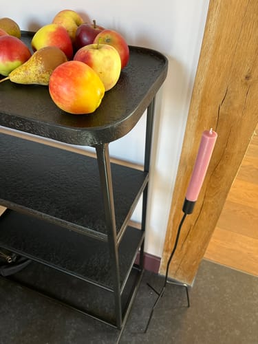 Recensent toont de zwarte Winston sidetable met een getextureerde afwerking, met fruit op het bovenste blad.