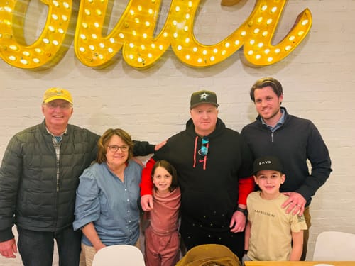 Customer's son wearing the black SAVD Perforated Snapback while posing with family.