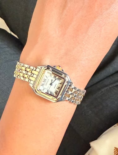Close-up of the customer's GREALY DE MAINS watch, showing its detailed square face and two-tone band.