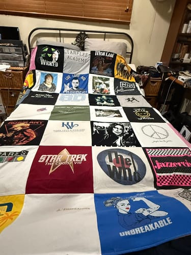 Customer's large Premium T Shirt Quilt spread across a bed, showing many colorful shirt designs.