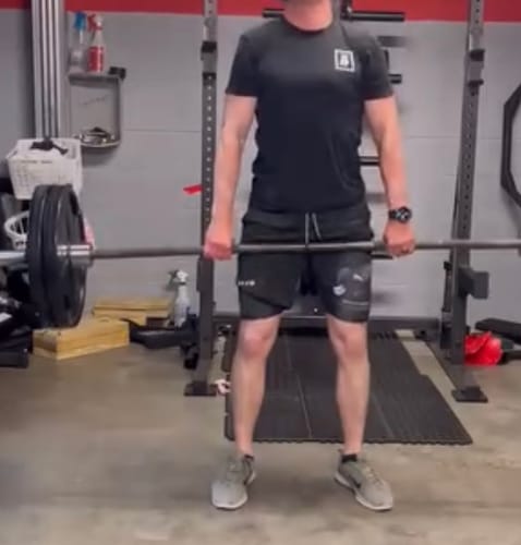 Reviewer lifting weights in a gym while wearing the black Joshua 1:9 Lion Performance Shorts.