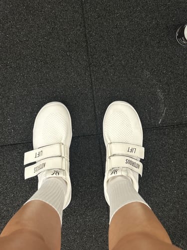 Customer's overhead view of their white Notorious Lifters Gen 2X shoes fastened securely on their feet on a gym floor.