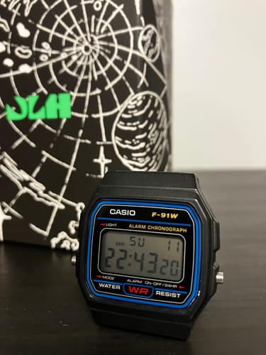 Primer plano del reloj Casio Vintage F-91W de un cliente, con su caja de diseño vintage al fondo.