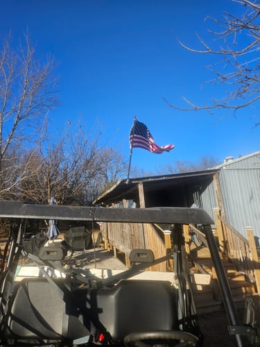 Reviewer's Prestige House Flag Pole mounted on a building, with the American flag waving against a clear blue sky.