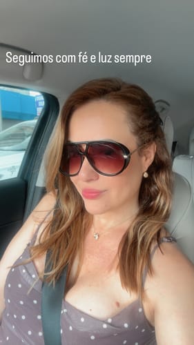 Avaliadora usando os Óculos Veneza grandes com lentes degradê dentro de um carro.
