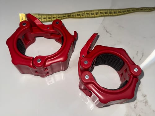 Customer's pair of red Olympic Flip Lock Collars V2 on a white marble surface, with a measuring tape in the background.