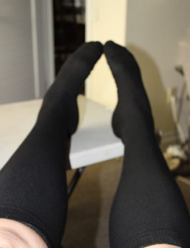 A customer's view of their feet propped up wearing the black compression socks.
