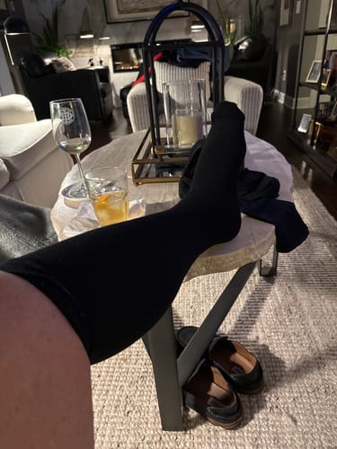 Reviewer relaxing with their leg propped up, wearing a black Performance Eucalyptus Compression Sock.