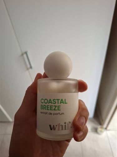 Customer holding the frosted glass bottle of Coastal Breeze perfume in their hand.